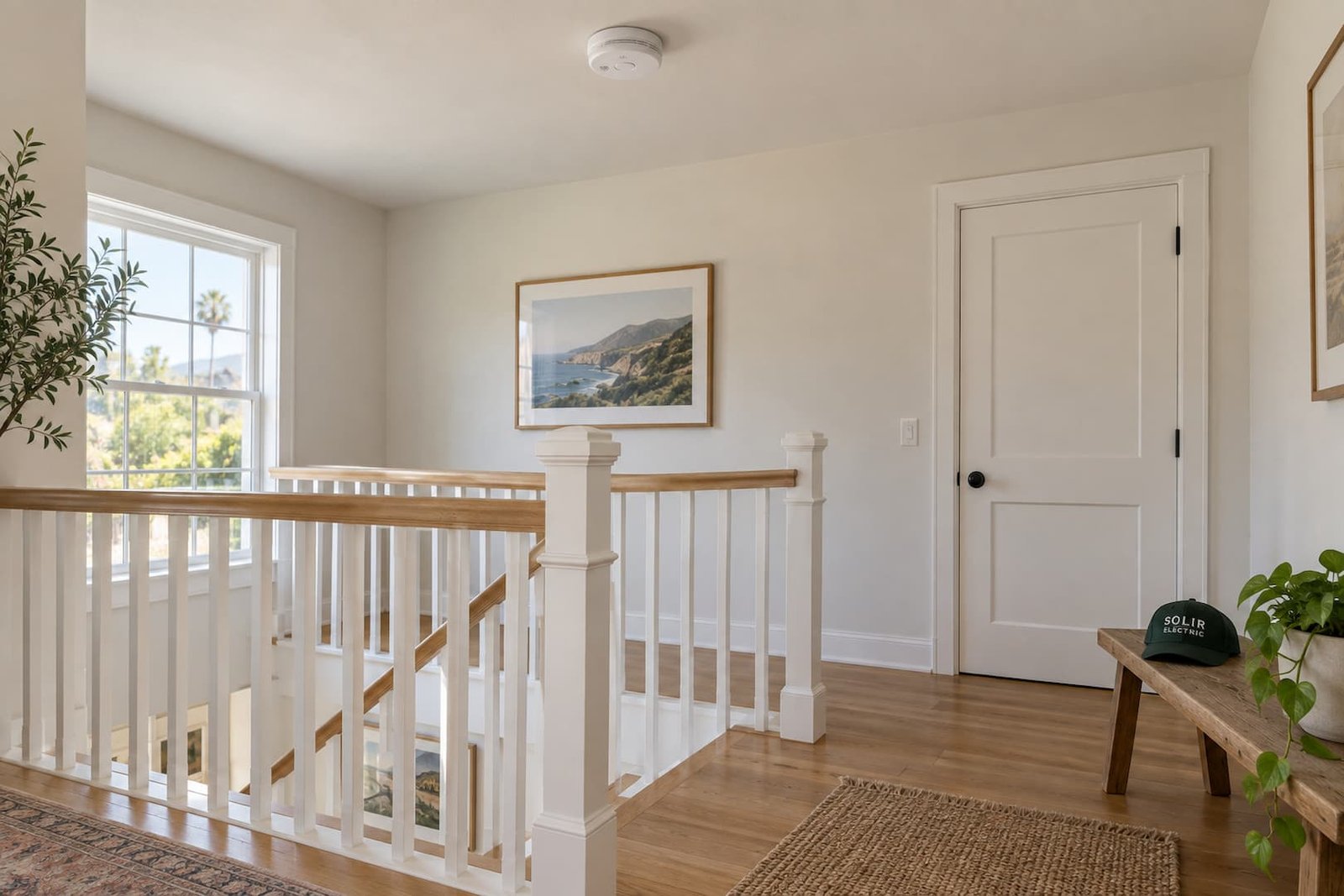Ceiling-mounted smoke alarm above a bright stair landing, with a Solir Electric cap on a bench.